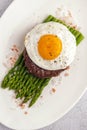 Beefsteak from minced beef with fried eggs and fresh green asparagus.