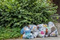 Beek, South Limburg / Netherlands. Juli 17th. 2020. Plastic garbage bags stacked next to a green foliage plant on the street