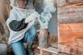 Beekeeper, bee suit and smoke, fog and smoking a beehive box outdoor on a farm, working and safety protection