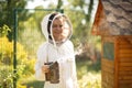 Beekeeper girl in white suit posing near a clue with a bee smoker Royalty Free Stock Photo