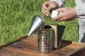 The beekeeper kindles a smoker to fumigate the hive. Breeding honey bees in the apiary Royalty Free Stock Photo