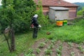 Farmer mows grass around bee hive and wears protective work wear Royalty Free Stock Photo