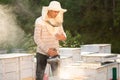 A beekeeper smokes bees in the process of collecting honey in wooden colored beehives. Beekeeping tool Royalty Free Stock Photo