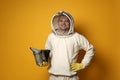 Beekeeper in uniform with smokepot on yellow background Royalty Free Stock Photo