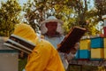 Beekeepers checking honey on the beehive frame in the field. Small business owners on apiary. Natural healthy food