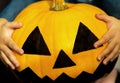 Jack's pumpkin head for Halloween in the blurry hands of a child. A little girl holds a big terrible pumpkin close-up. Royalty Free Stock Photo