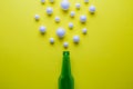 Flat lay of green beer bottle and bubbles made of styrofoam balls against yellow background minimal creative drink concept