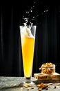 Beer being poured into glass with gourmet snacks for beer, splash, black background. vertical image. place for text