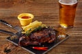 Beer being poured into glass with gourmet steak and french fries on wooden background. Royalty Free Stock Photo