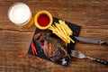 Beer being poured into glass with gourmet steak and french fries on wooden background. Top view Royalty Free Stock Photo