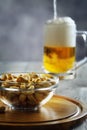 Beer on a blue background with cashew nuts.