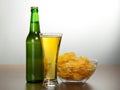 Beer bottle, bowl with chips and a damp glass Royalty Free Stock Photo