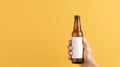 Beer Bottle Mock-Up. Male hands holding a beer bottle on a yellow background Royalty Free Stock Photo