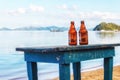 Beer bottles of cold, fresh beer, against the background of the sea or ocean standing on an old wooden table Royalty Free Stock Photo