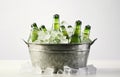 Beer bottles in metal basket with ice cubes on light background for party drink