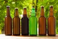 Beer bottles on table on blurred park background, summer drinks