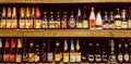 Beer bottles on wooden shelf with different sorts of lambic, lager, ales, strong stouts