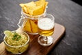 Beer and a bowl of guacamole with nachos on an old black wooden table Royalty Free Stock Photo