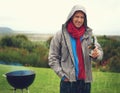 Beer and braaing is one of the best combos ever. a cheerful man barbecuing in the rain while drinking a beer.