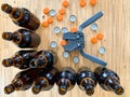 Beer brewing at home, plastic capper to put metal caps on bottles, brown glass beer bottles and orange crown caps on wooden Royalty Free Stock Photo