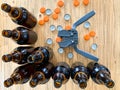 Beer brewing at home, plastic capper to put metal caps on bottles, brown glass beer bottles and orange crown caps on wooden