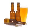 Glass of cold beer with several brown lager pils bottles isolated on white background Royalty Free Stock Photo