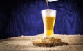 Beer jet pouring into a crystal glass on a blue wooden textured background Royalty Free Stock Photo