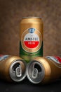 Beer cans. Full and two empty open beer cans on a dark background. AMSTEL world famous brand in the Netherlands. Selective focus.