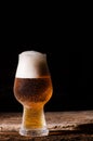 Beer. Cold Craft light Beer in a glass with water drops on the wooden table over the black background Royalty Free Stock Photo