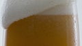 Beer foam flowing glass in super slow motion close up. Froth drink overflowing.
