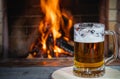 Beer with foam in the mug, on wooden table, against cozy fireplace background