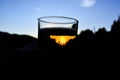 Beer in a glass against the background of the sun at sunset