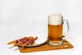 Beer in glass mug on wooden table and bread sticks wrapped in ham on a plate Royalty Free Stock Photo