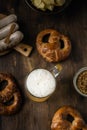 Beer glass with pretzels, bratwurst and snacks on rustic wooden table