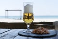 Beer glass and shrimps on stone plate in shadow table against sunny beach blurred background of the sea. Royalty Free Stock Photo