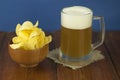 Beer glass with beer and smoked fish close-up. Beer mug with beer and potato chips, crackers on a wood background and copy space Royalty Free Stock Photo