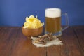 Beer glass with beer and smoked fish close-up. Beer mug with beer and potato chips, crackers on a wood background and copy space Royalty Free Stock Photo