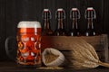 Beer glass on table with crate full of bottles, with brewing barley and wheat bunch Royalty Free Stock Photo