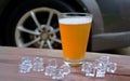 Beer in glass on wood table with ice, car background. Royalty Free Stock Photo