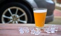 Beer in glass on wood table with ice, car background. Royalty Free Stock Photo