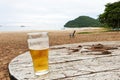 Beer glass on wood table at the peaceful sea sand beach with nature cloudy sky background landscape in Thailand Royalty Free Stock Photo