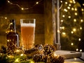 Beer in glass on wooden background with Christmas lights and pine cones Royalty Free Stock Photo