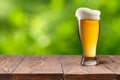 Beer in glass on wooden table against green Royalty Free Stock Photo