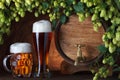 Beer glasses and beer barrel with fresh hops