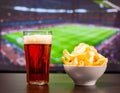 Beer glasses and chips in front of tv, football at home Royalty Free Stock Photo