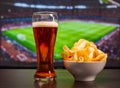 Beer glasses and chips in front of tv, football at home Royalty Free Stock Photo