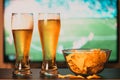 beer glasses and chips in front of tv - watching world cup football at home - soccer supporters Royalty Free Stock Photo