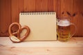 Beer mug, empty notebook and pretzel on wooden table. Royalty Free Stock Photo