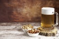 Beer mug with foam and bowls of peanuts and almonds Royalty Free Stock Photo