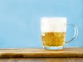 Beer mug half full and tall froth. Lager in a glass. Blue wall background. Copy space Royalty Free Stock Photo